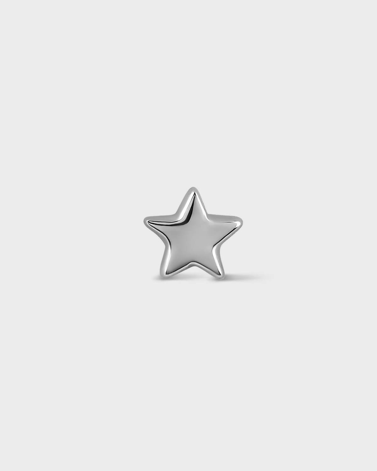 Silver star-shaped earring on a light gray background