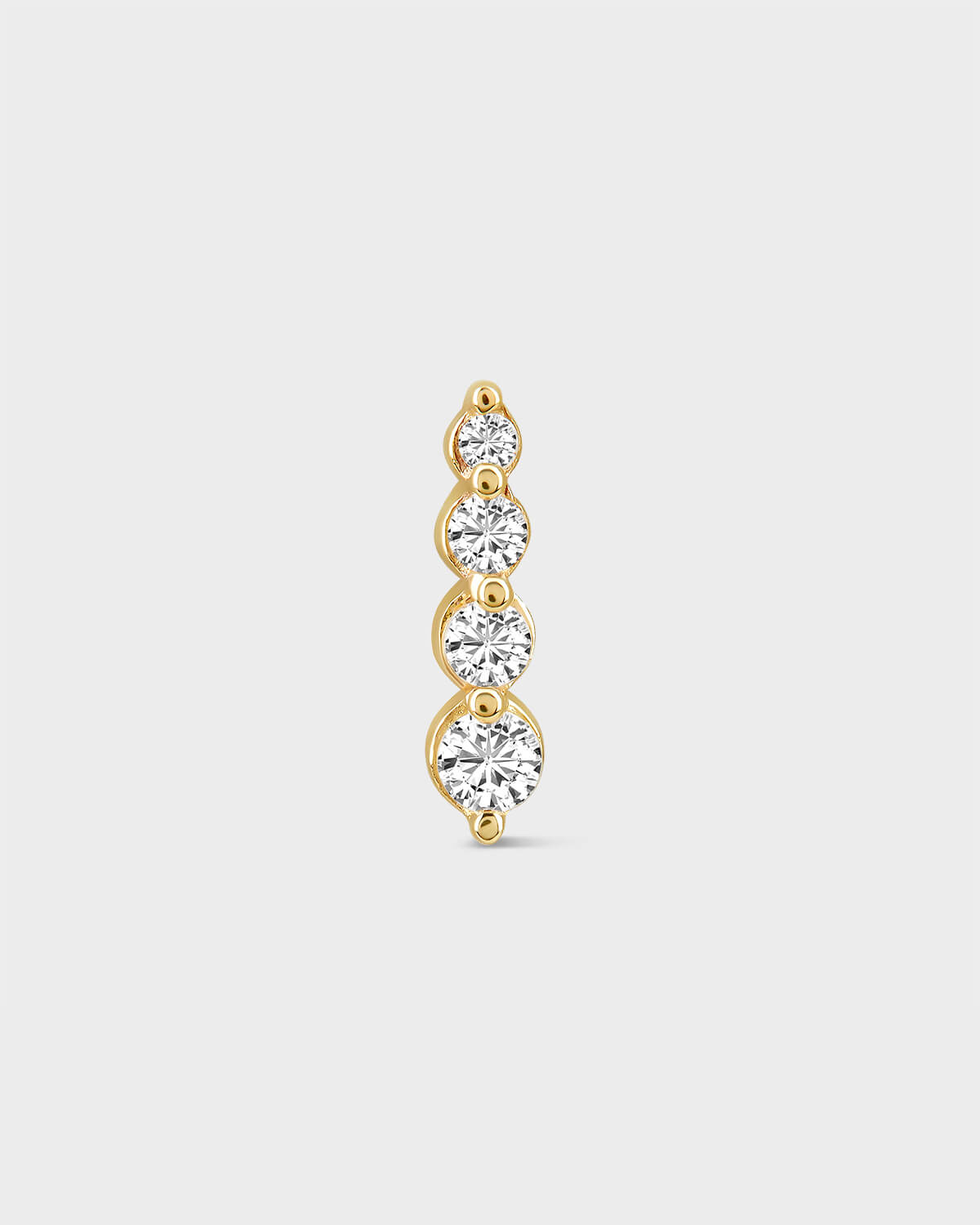 Gold earring with four clear gemstones on a light gray background