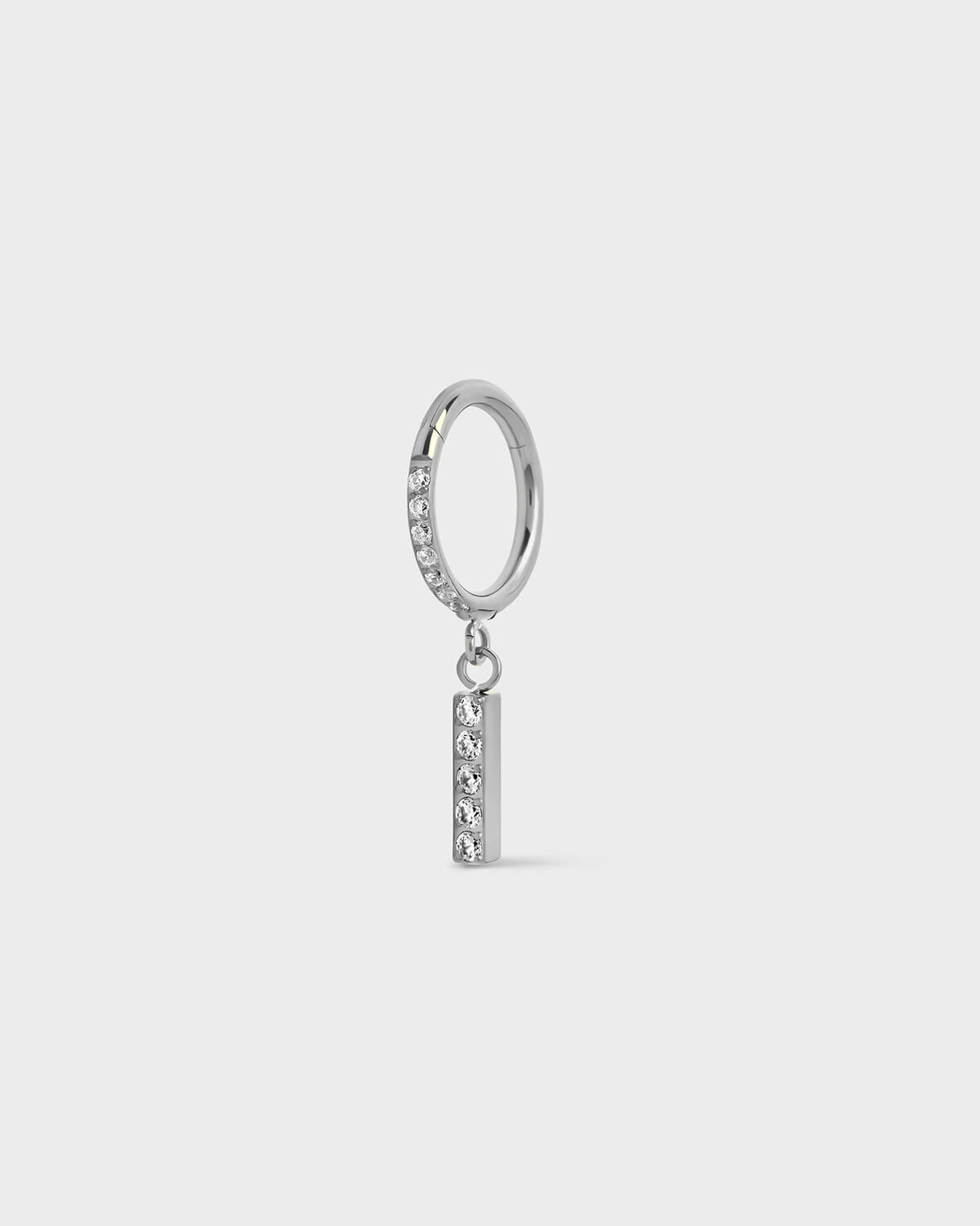 Polished silver titanium ring with pavé set gems along the front edge, finished with a vertical bar drop accented by a row of matching pavé stones. On a light gray background.