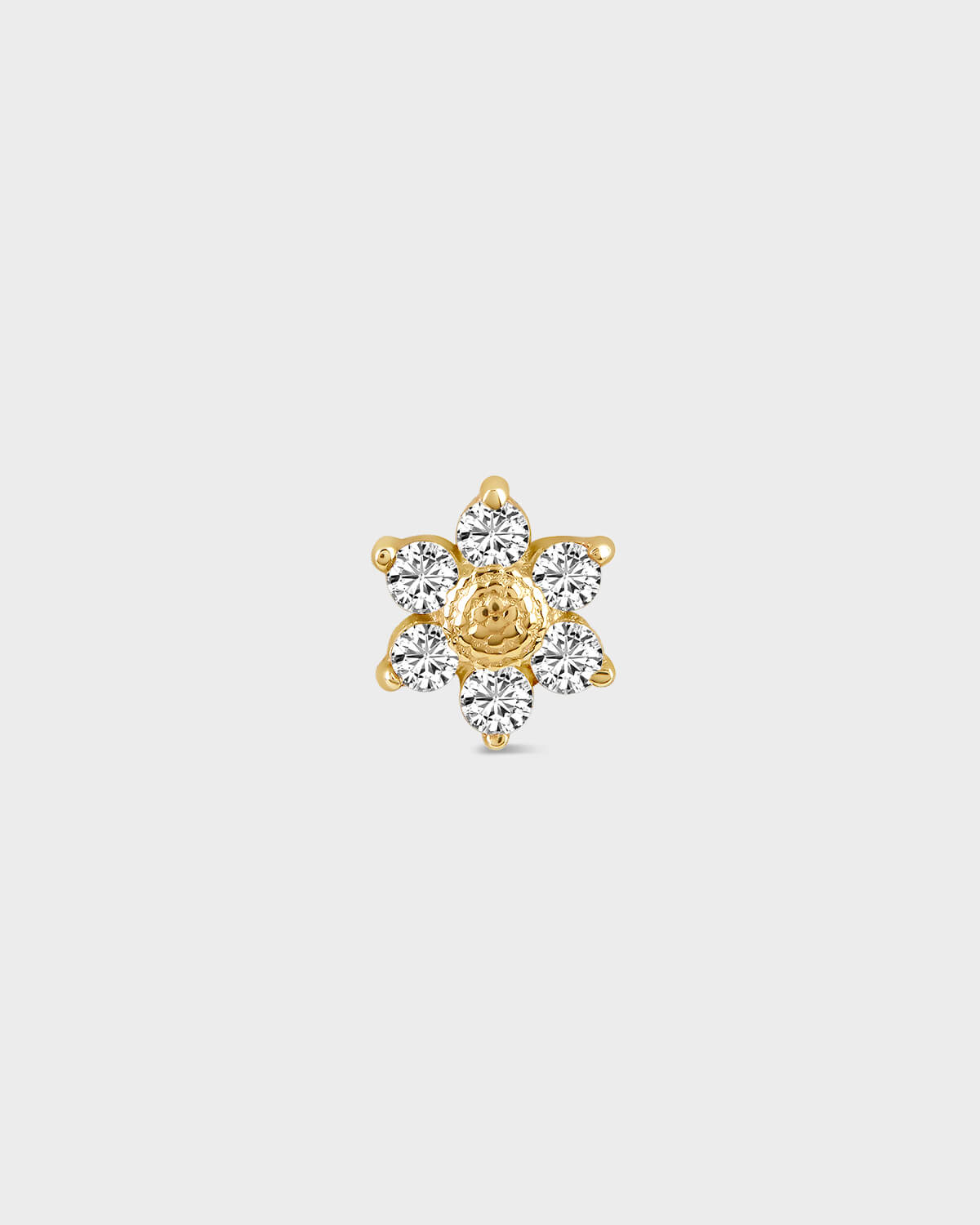 Gold and diamond earring on a light gray background