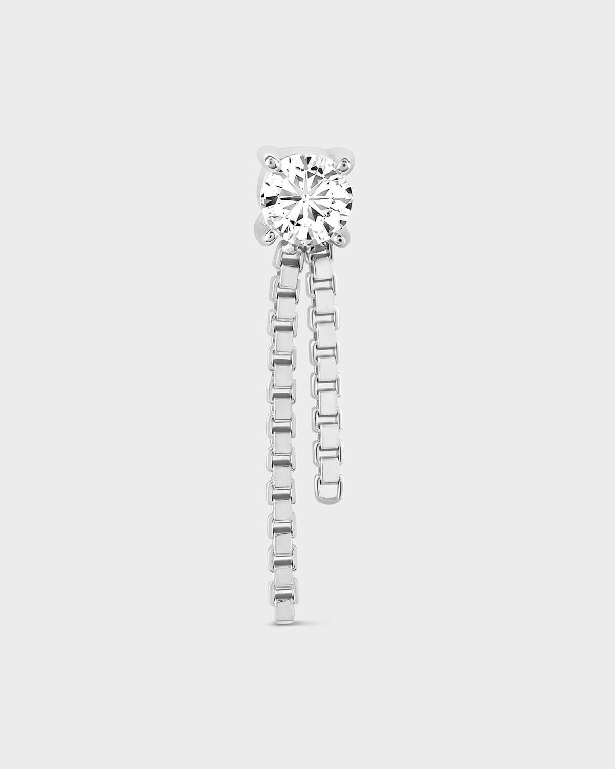 Gold solitair earring with two small graduated box chains dangling on a light gray background