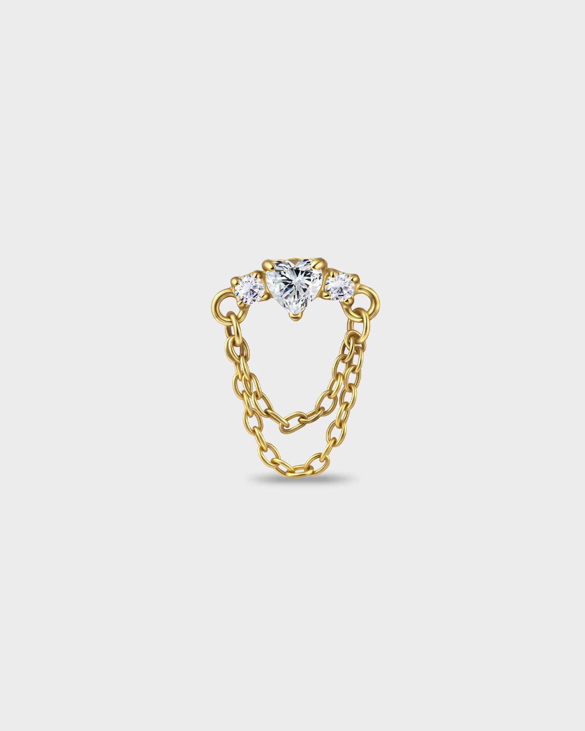 Gold titanium earring with a heart-cut clear stone set between two smaller round-cut stones, finished with a double chain detail on a light gray background.