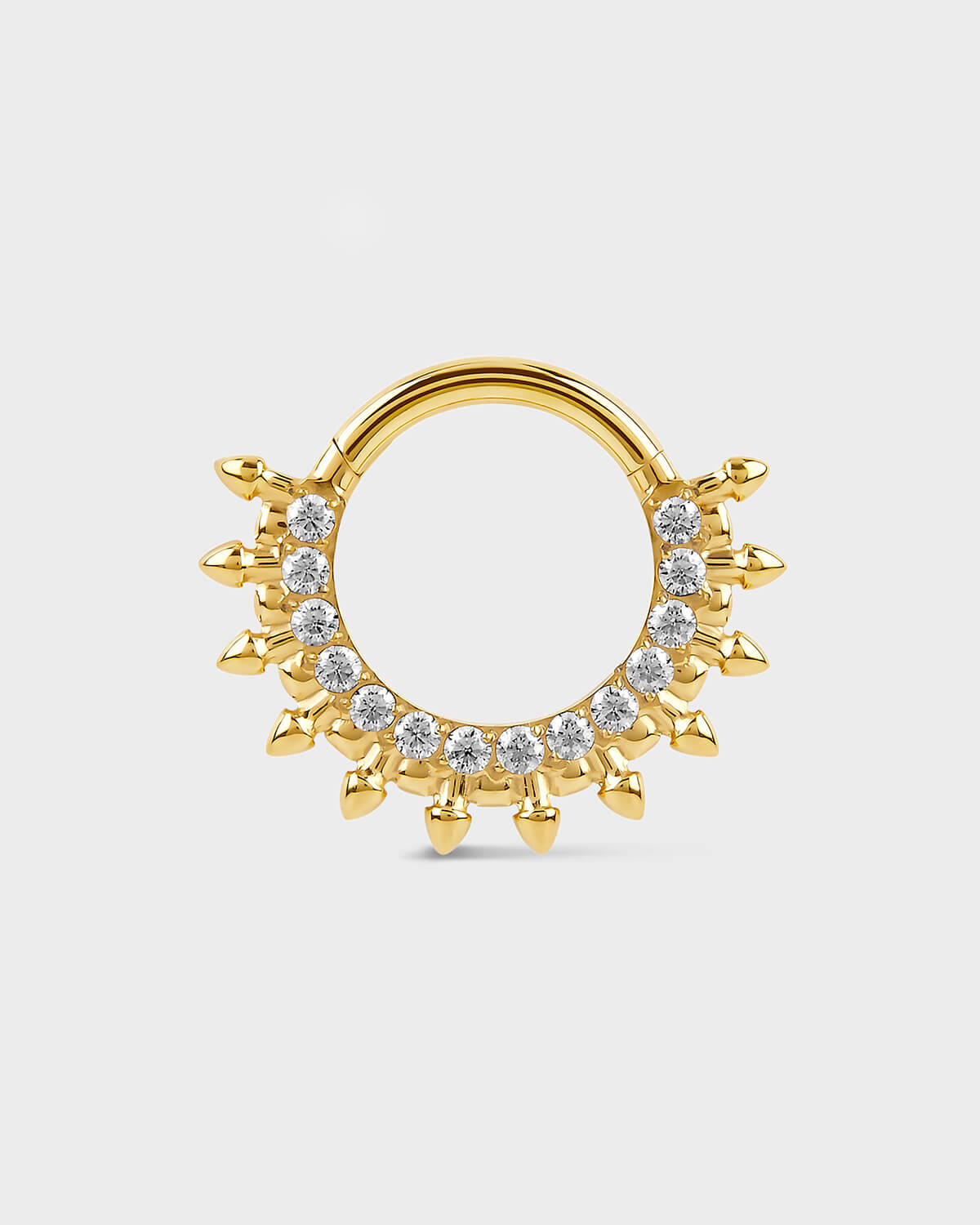 Gold septum daith ring with diamond-like stones on a light gray background