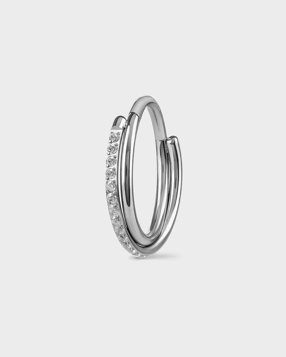 Polished silver titanium with double twist ring. One pave and the other plain. Clear gemstones. Sat on a light gray backround.