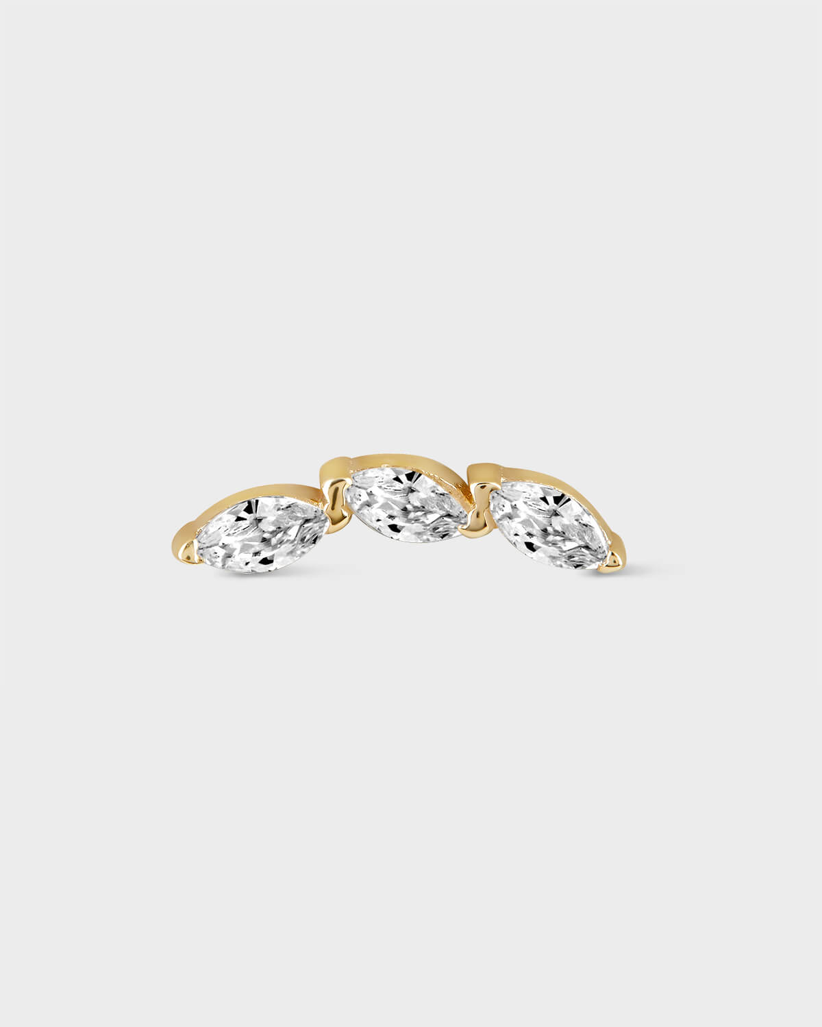 Gold earring with three clear gemstones on a light gray background