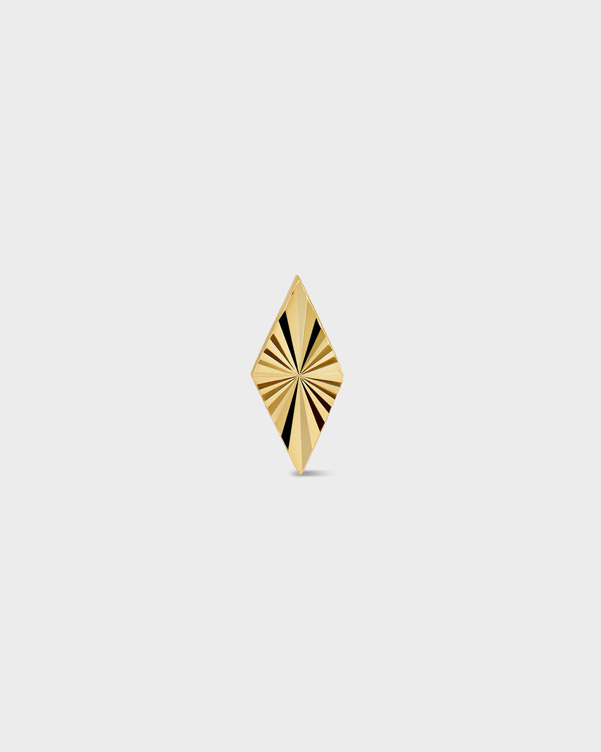 Diamond shape gold earring with laser engraved lines on a light ray background