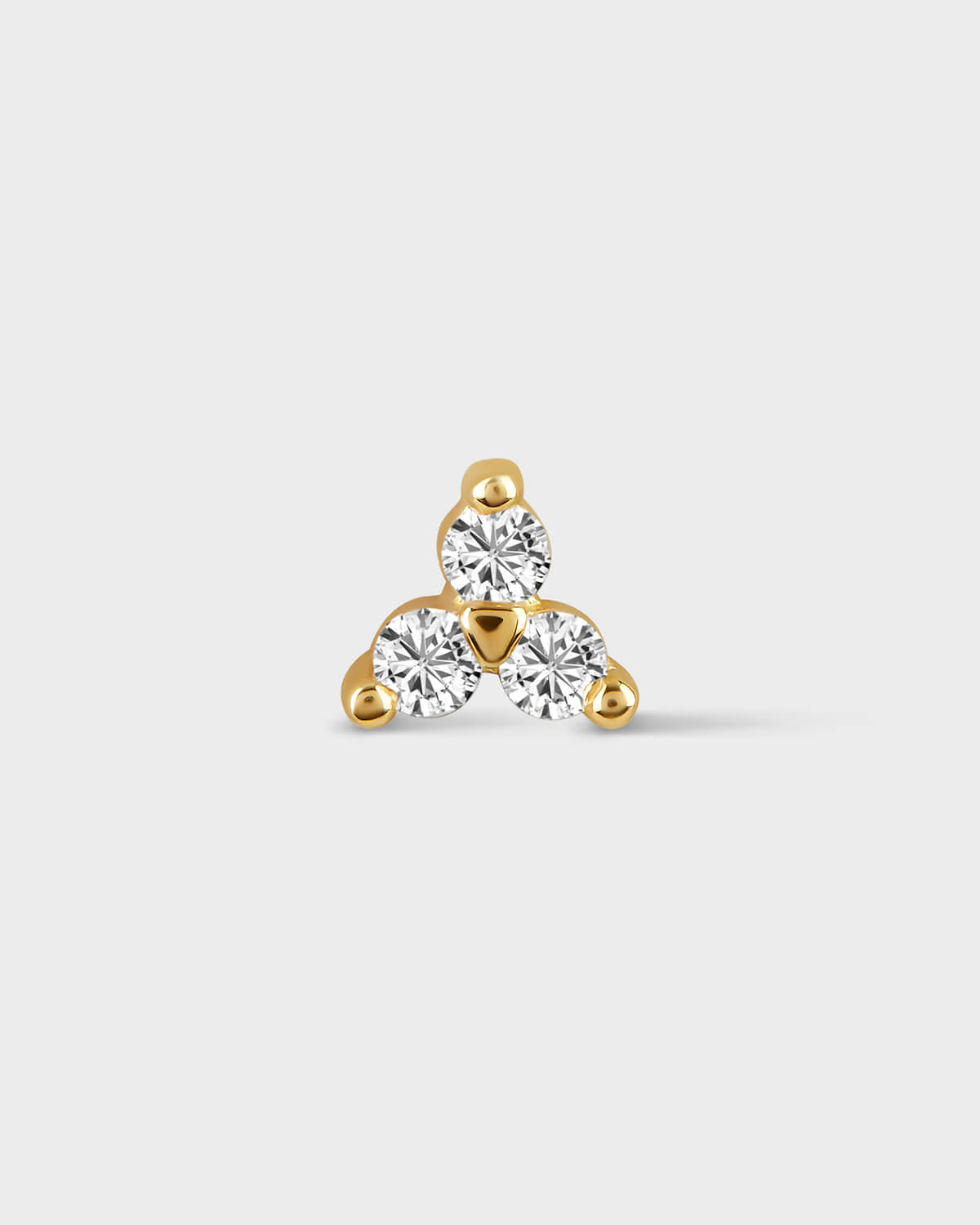 Gold earring with three clear gemstones on a light gray background