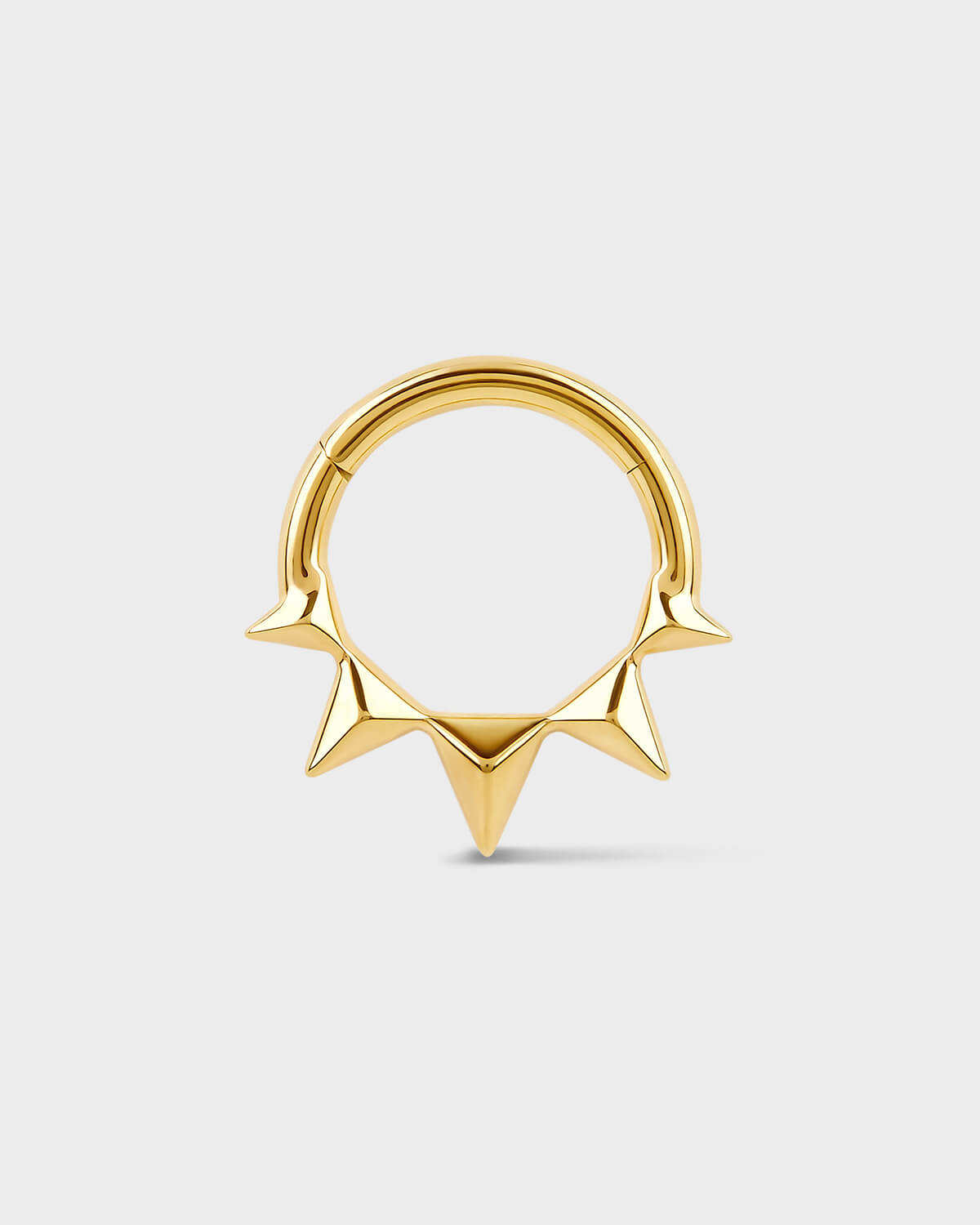 Gold septum ring with spikes on a light gray background