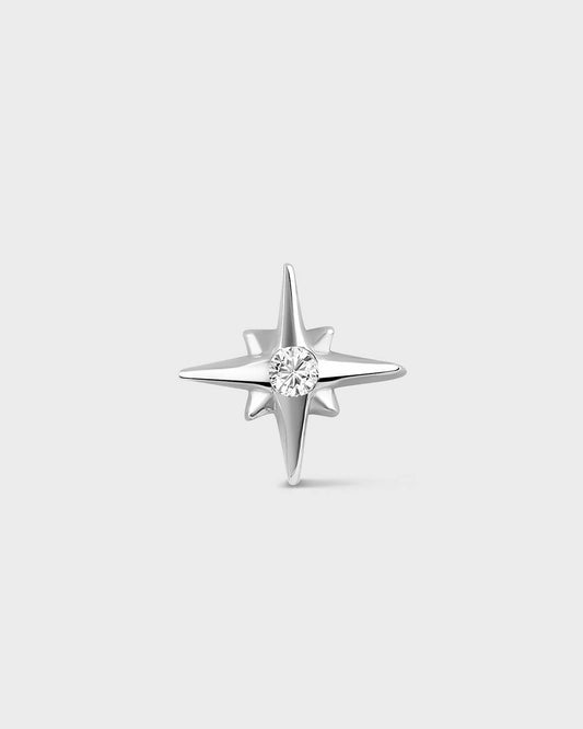 White gold star shape earring with central clear gemstone on a light gray backround