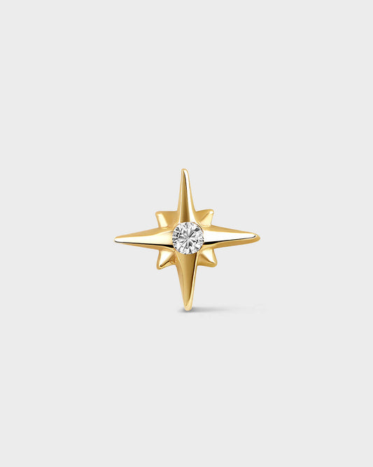 Yellow gold star shape earring with central clear gemstone on a light gray backround