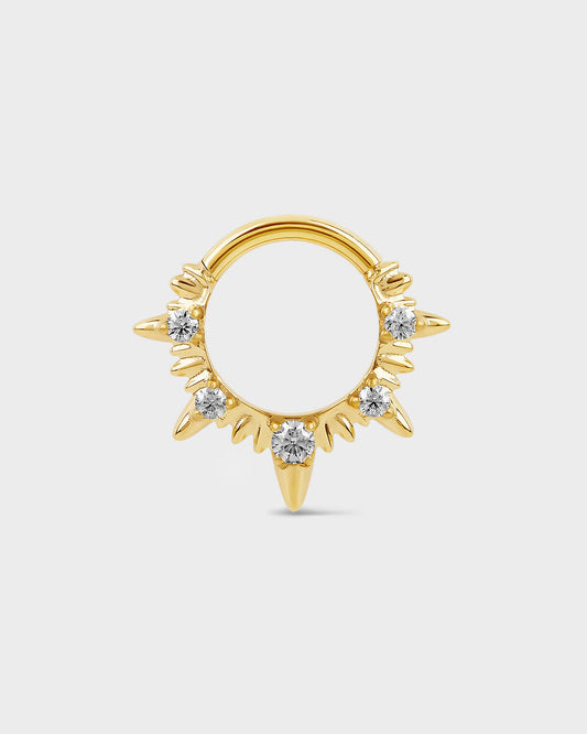 Gold septum ring with diamond-like stones on a light gray background