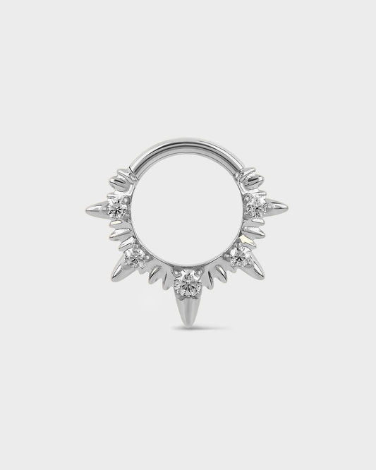 Polished titanium septum ring with diamond-like stones on a light gray background