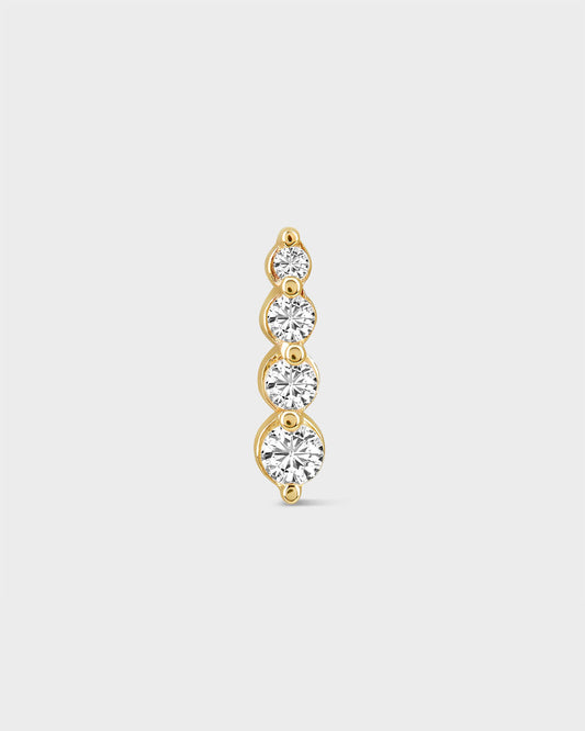 Gold earring with four clear gemstones on a light gray background