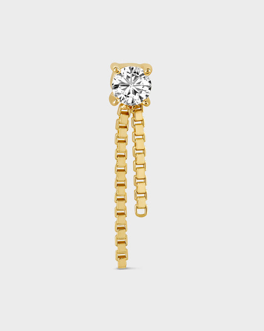 Gold solitair earring with two small graduated box chains dangling on a light gray background