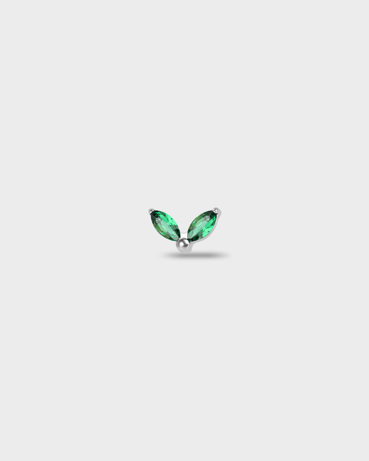 Polished titanium earring with two marquise-cut emerald green stones set in a simple leaf-style arrangement, on a light rgray background.