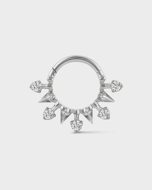 Polished silver titanium daith or septum ring with alternating spikes and solitaires on a light gray background.