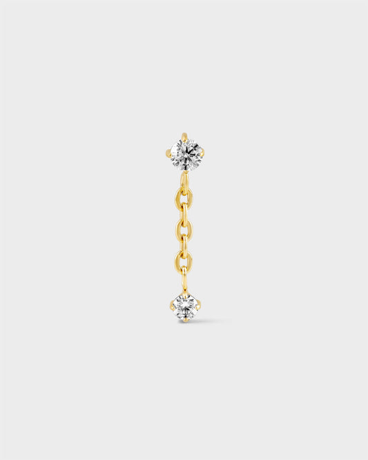 Gold titanium earring with solitaire and chain dropping to another smaller solitaire on a light grey background.