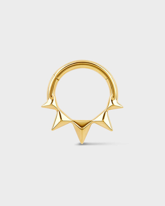 Gold septum ring with spikes on a light gray background