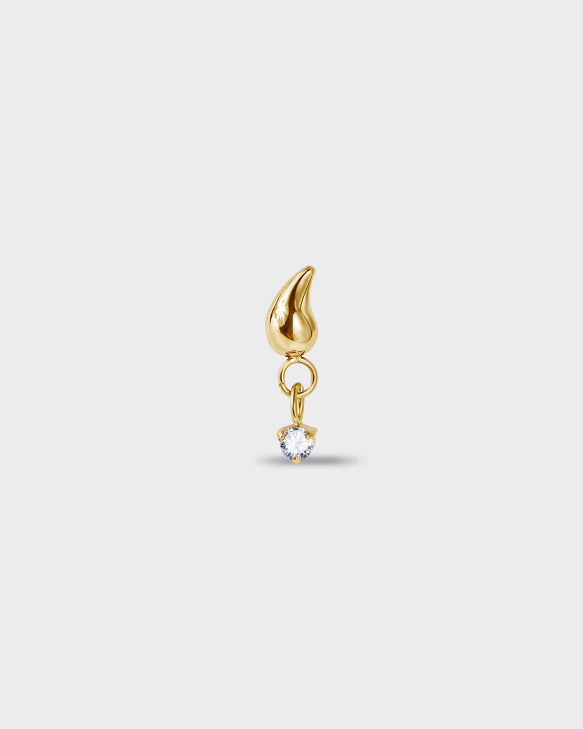 Gold PVD titanium earring with a tear drop shape at the top and a suspended clear solitaire dangle on a light gray background