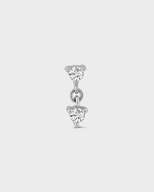 Silver earring with two clear gemstones on a light gray background